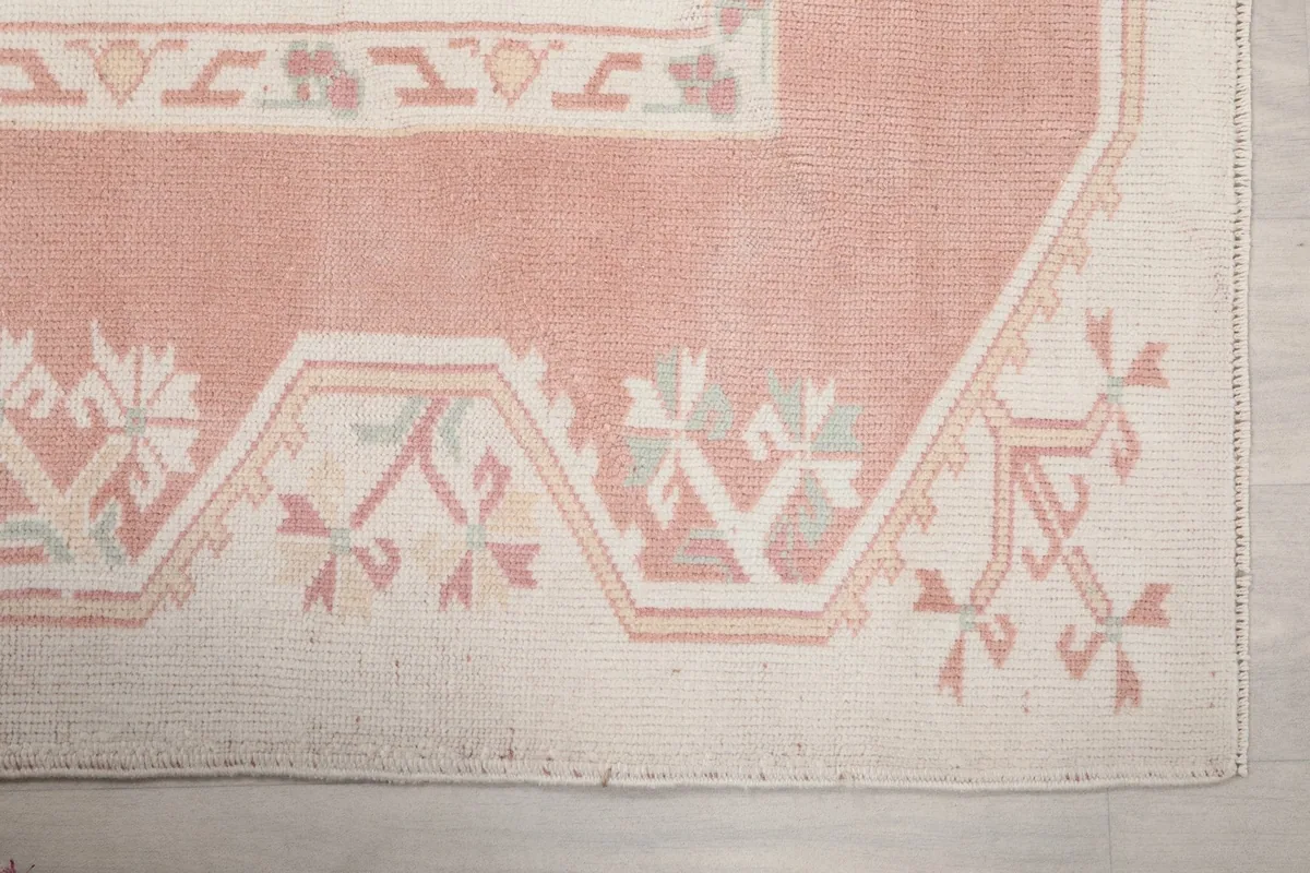 Detailed view of the corner of the rug, highlighting the rose border and ivory geometric patterns.