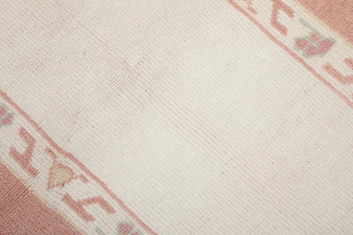 Close-up of the rug's low pile and weave texture in the ivory central field.