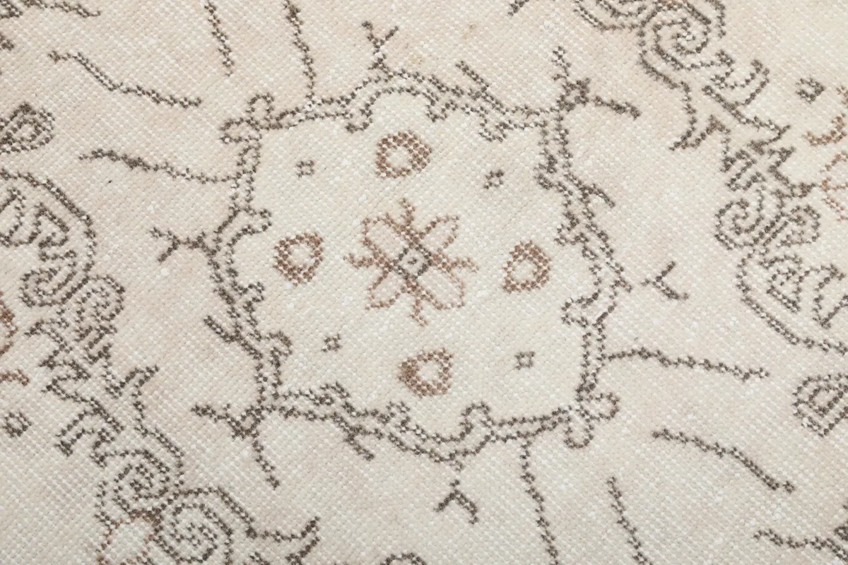 Close-up of the hand-knotted texture and faded brown pattern on ivory