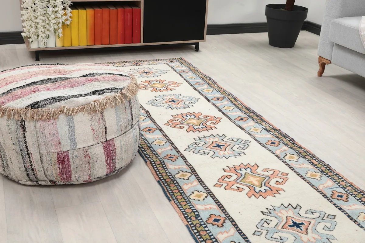 Close-up of one end of the runner rug next to a striped ottoman in a room