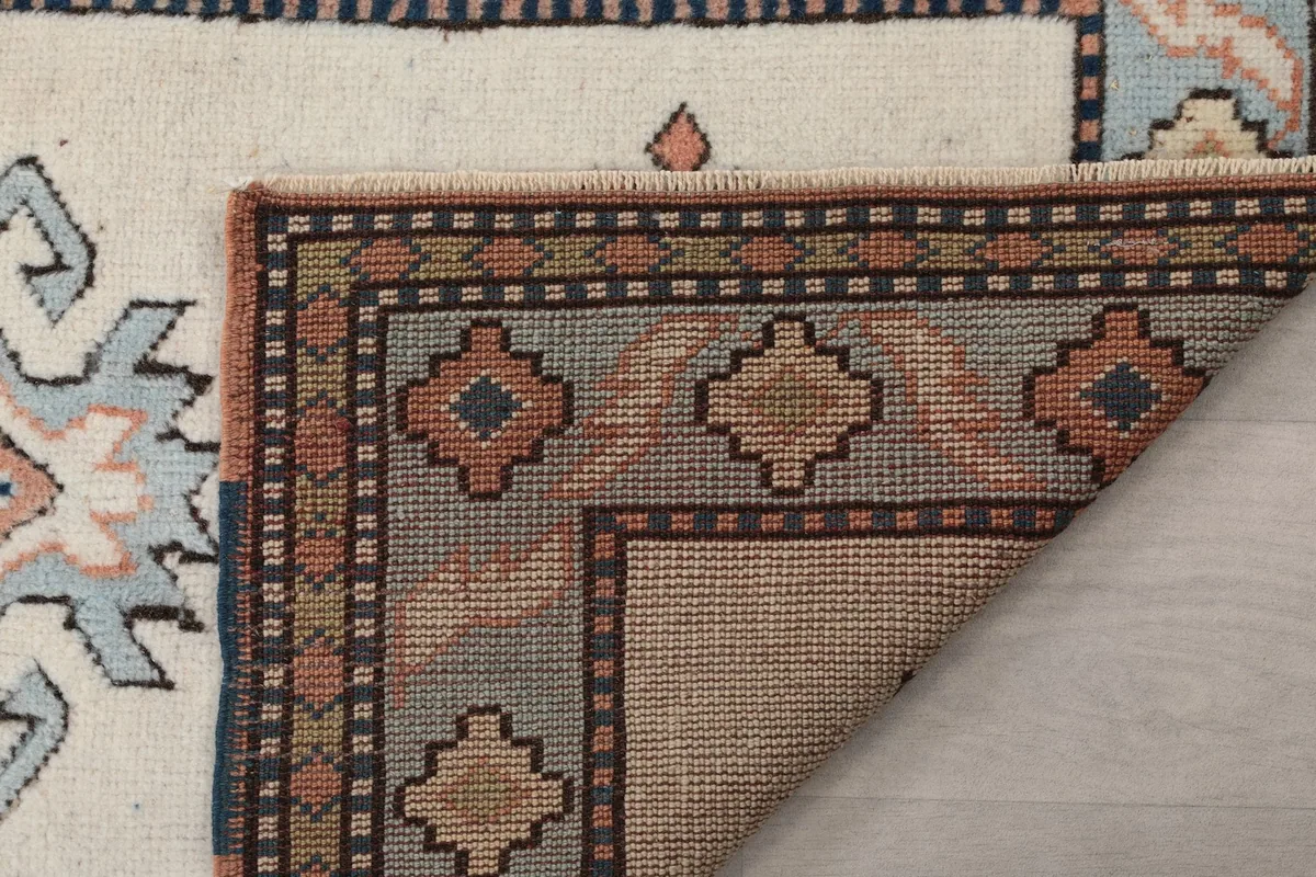 Underside view of the rug's corner, showing the tightly woven cotton foundation