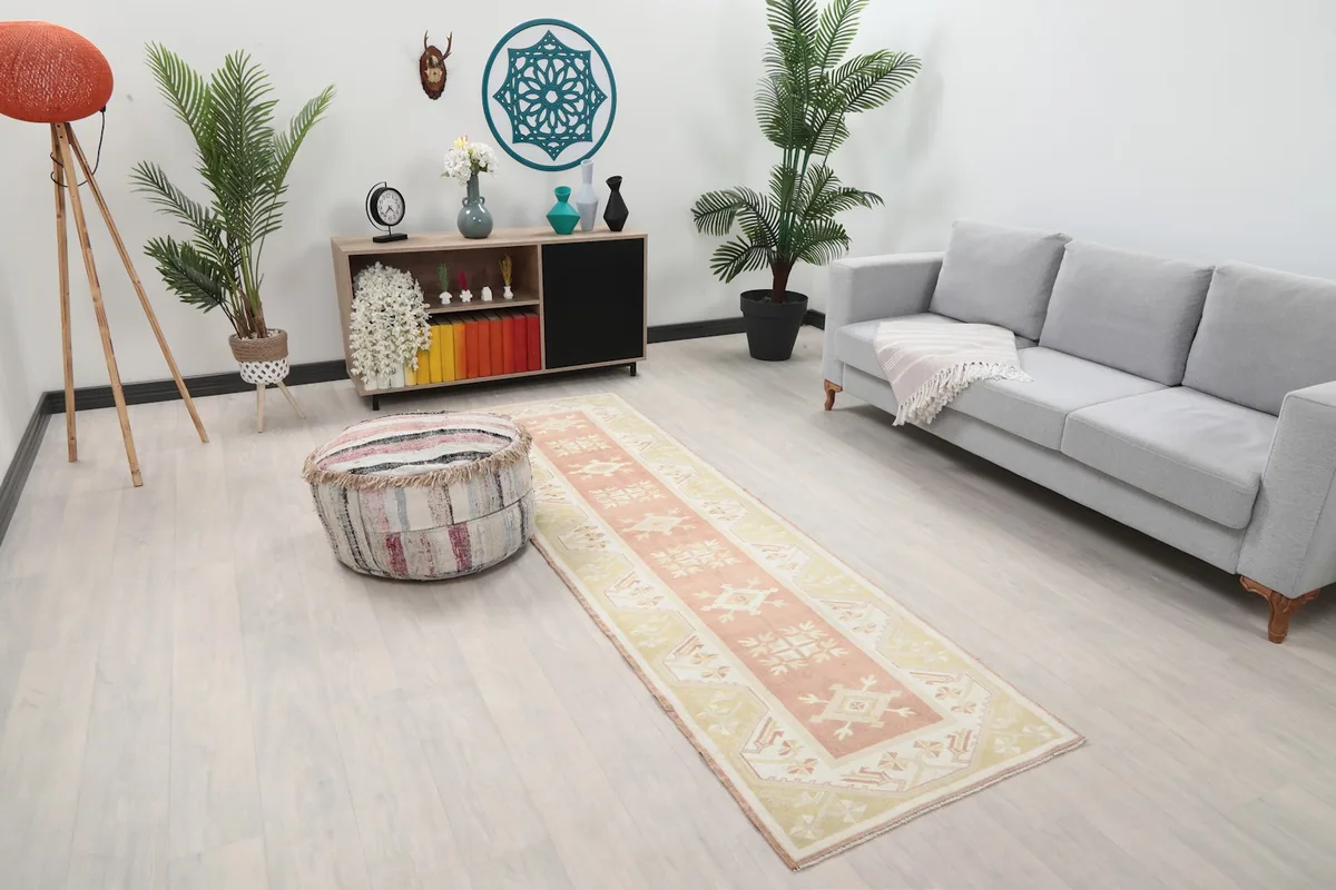 Angled view of the rose and beige runner rug in a room, showing its length and design.