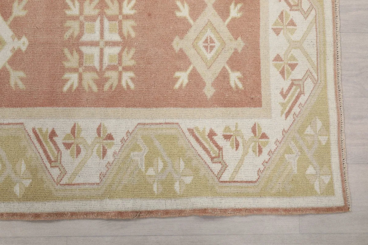Detailed view of the corner of the rug, showing the geometric border design in beige and ivory.