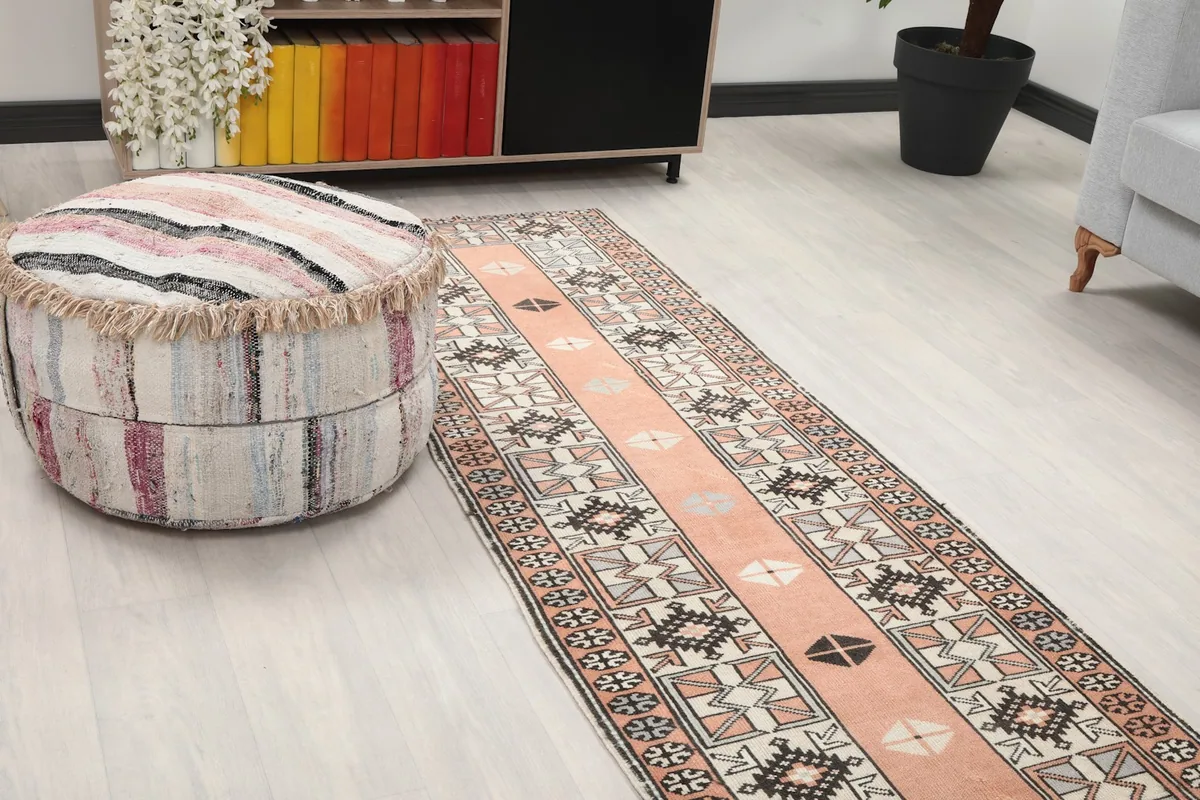 Close-up view of the runner's end in a room, next to a textured ottoman