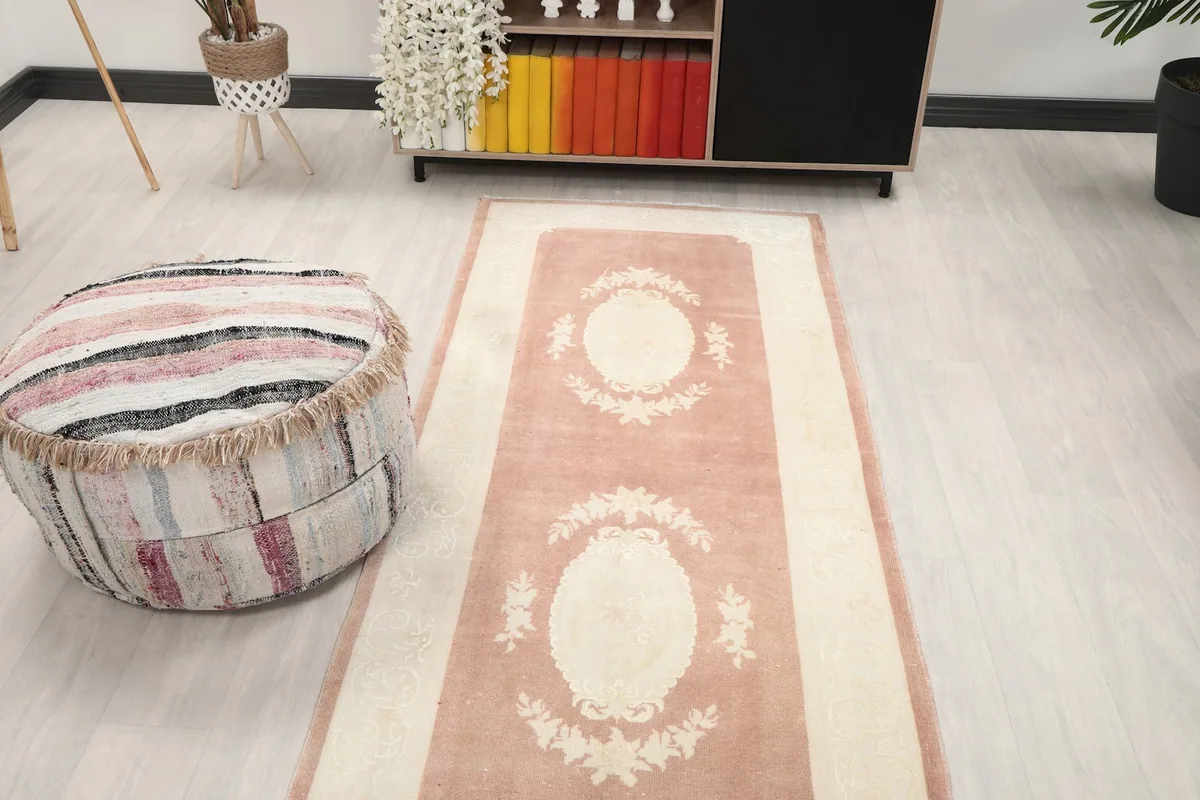 Angled view of the rose and ivory runner rug, showing its length and multiple medallions in a room