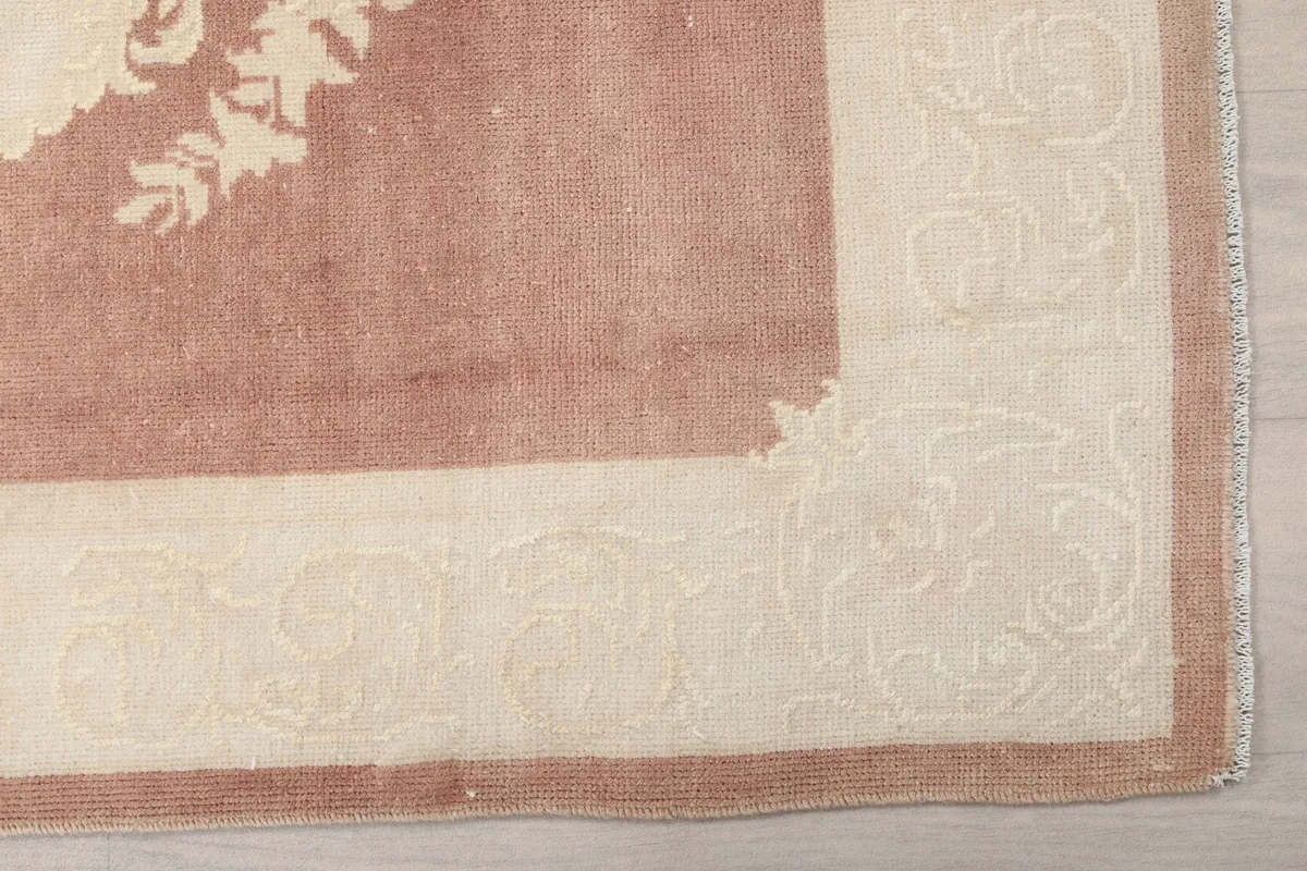 Detailed view of the ivory border with subtle geometric patterns and the rose field of the runner rug