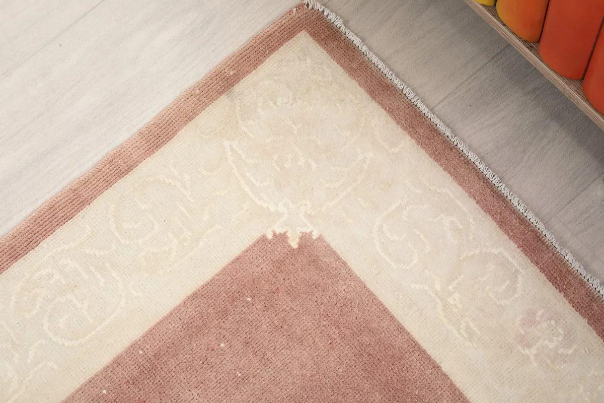 Corner detail of the runner rug, showing the transition from the rose field to the ivory border