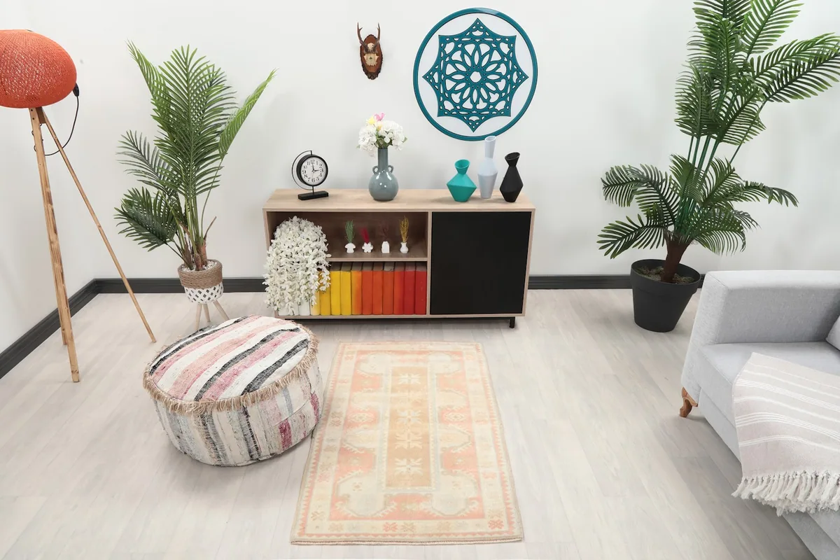Vintage rose and tan area rug in a modern room setting next to a gray sofa and pouf