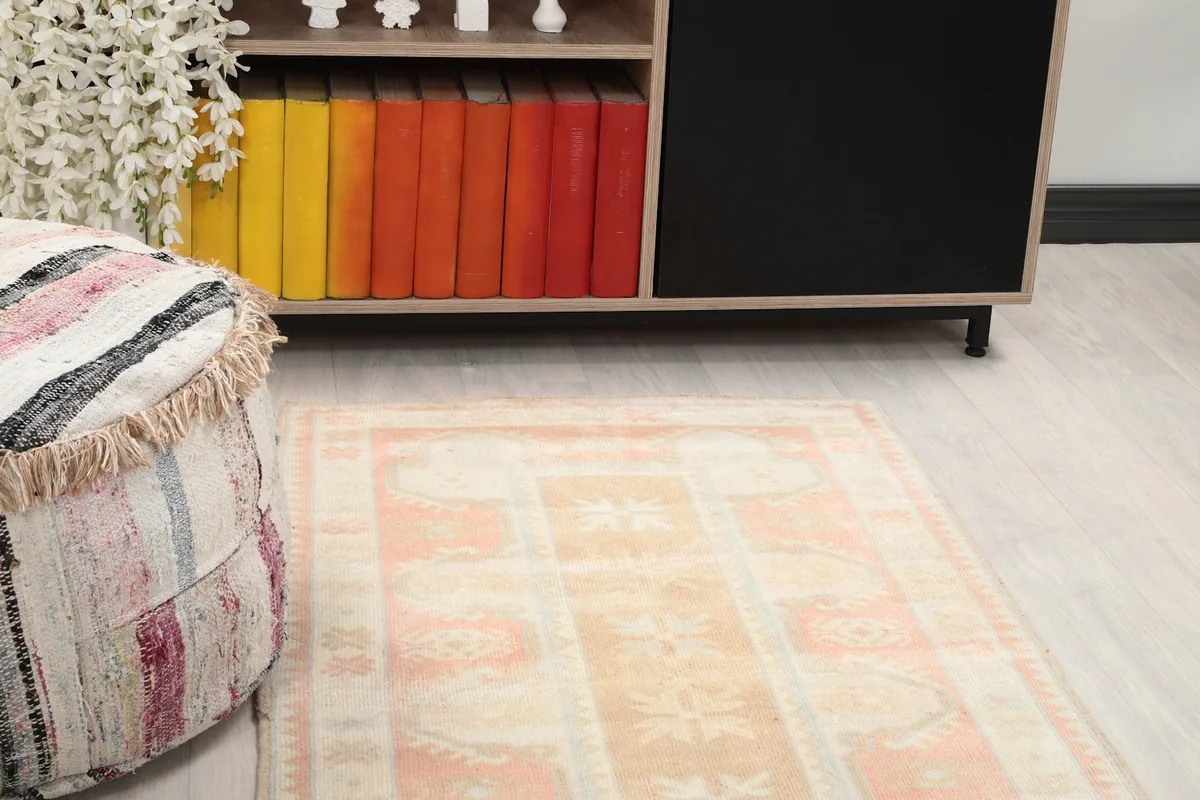 Close-up view of the rose, tan, and blue geometric patterns and soft colors of the rug