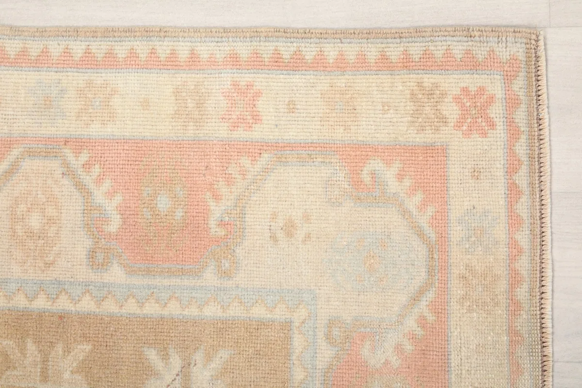 Detail of the outer border and corner motifs of the rose and tan vintage rug