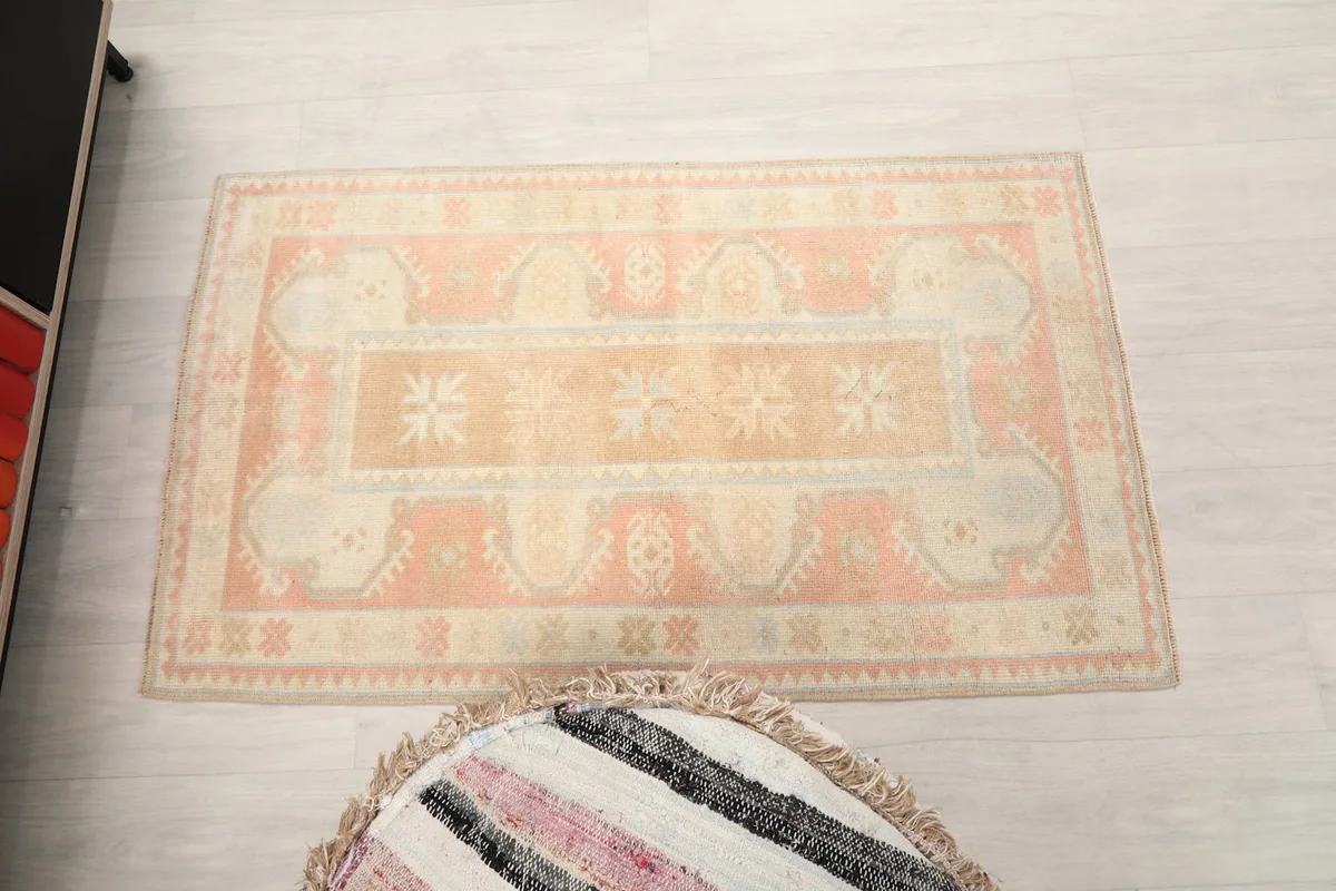 Full overhead view of the vintage rug, positioned in a room with a decorative pouf