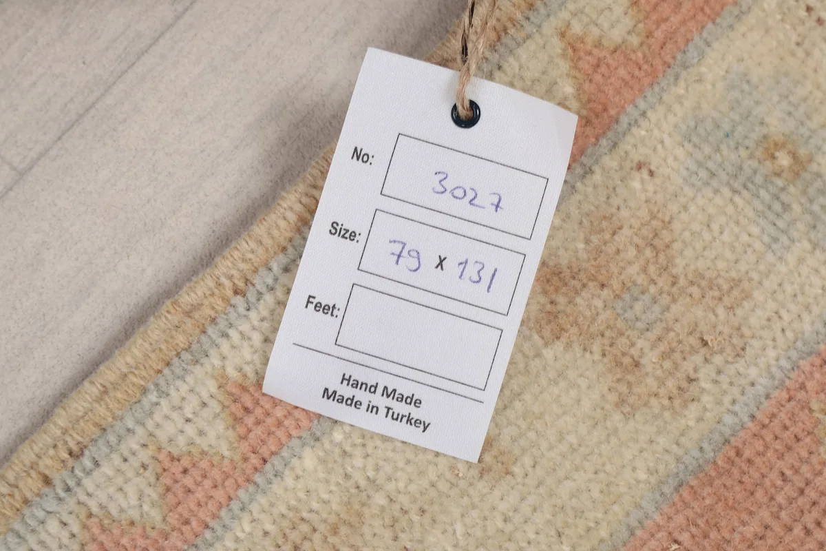 Product tag on the rug, displaying the size 79 x 131 cm and handmade in Turkey