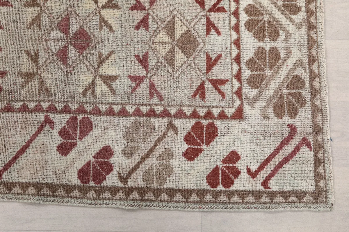 Detailed view of the rose and brown geometric motifs and border on the rug