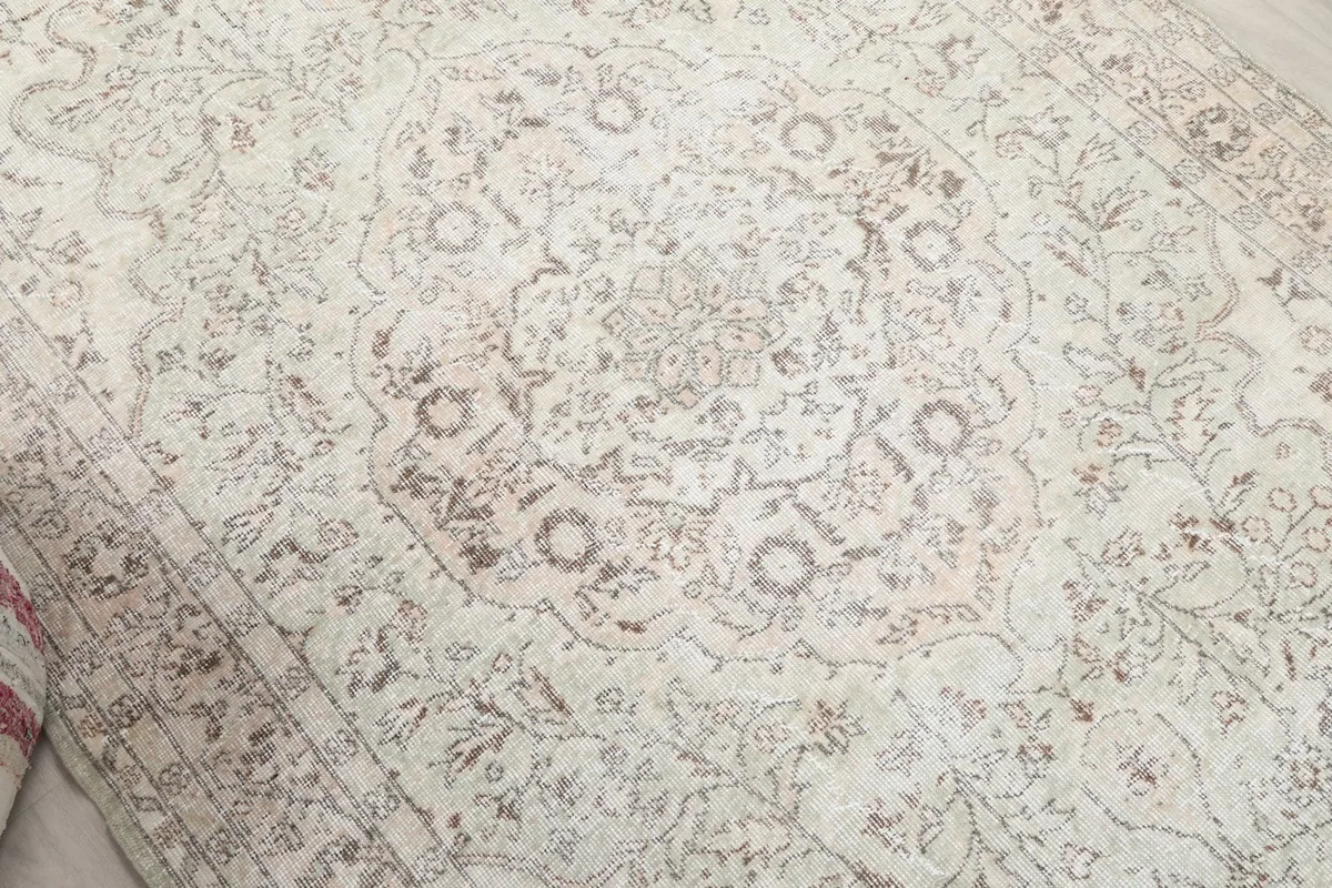 Mid-angle view highlighting the faded floral and medallion patterns on the ivory field.