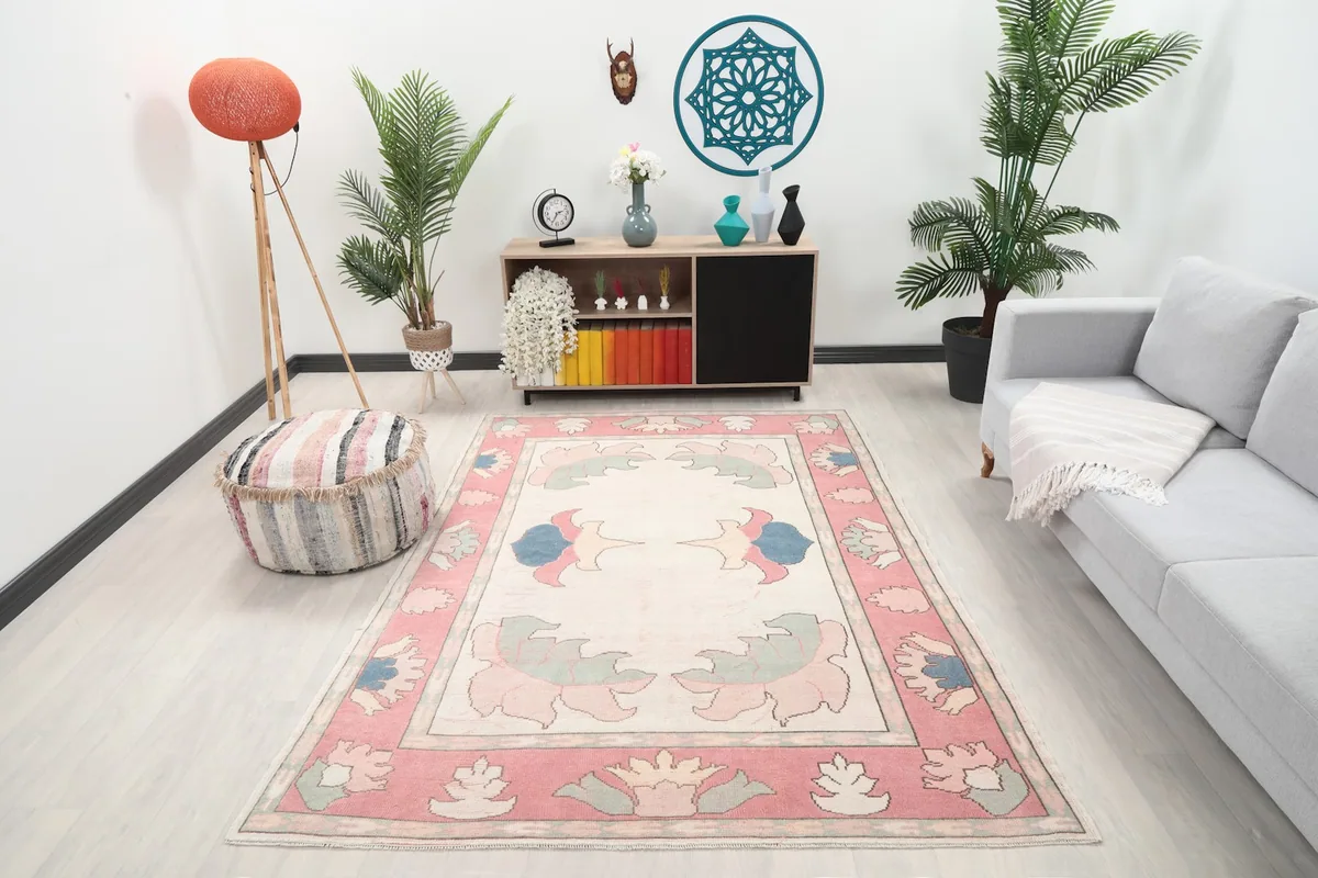 Rose and ivory rug in a modern living room setting with plants and gray sofa