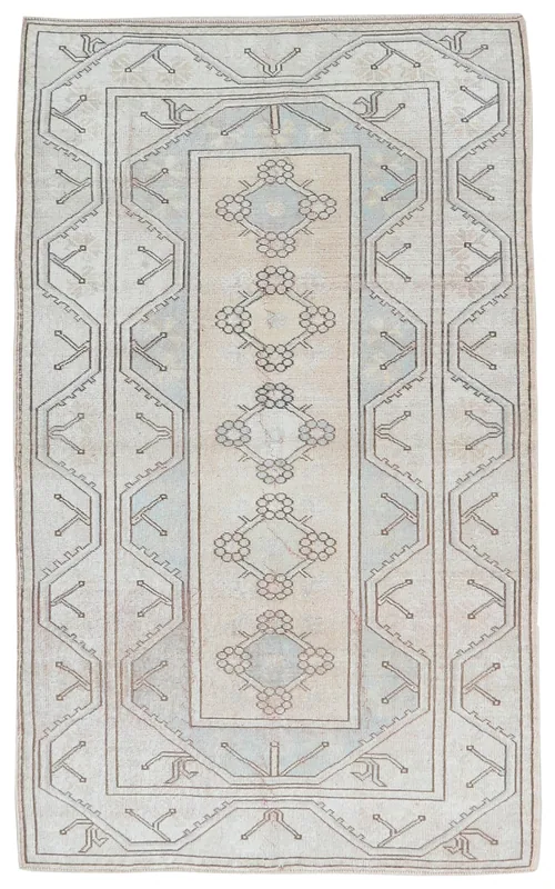 Full overhead view of the beige and blue geometric vintage Anatolian rug on a white background.