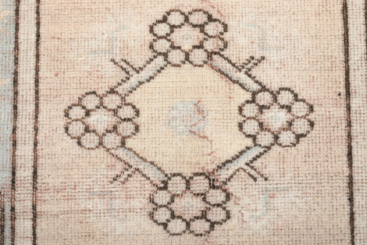 Close-up of a central floral-like geometric motif in beige with charcoal outlines.