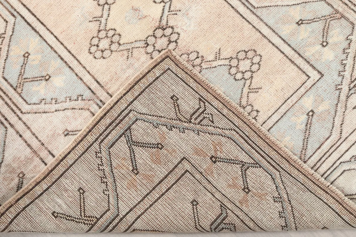 Folded corner of the rug, revealing the wool pile and cotton foundation.