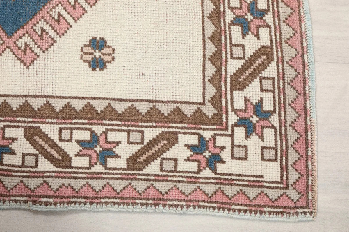 Close-up of the rug's corner showing the brown and pink geometric border patterns