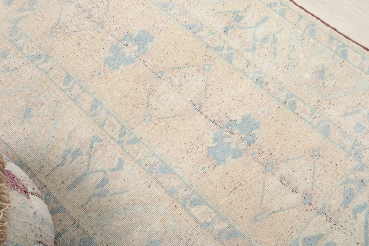 Angled view of the rug's field, showcasing the subtle color variations and hand-knotted texture.