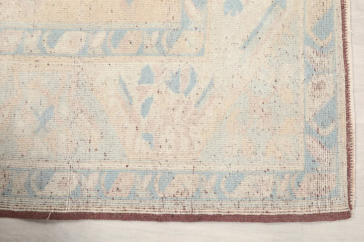 Detailed view of a corner of the rug, showing the blue geometric patterns and rust border.