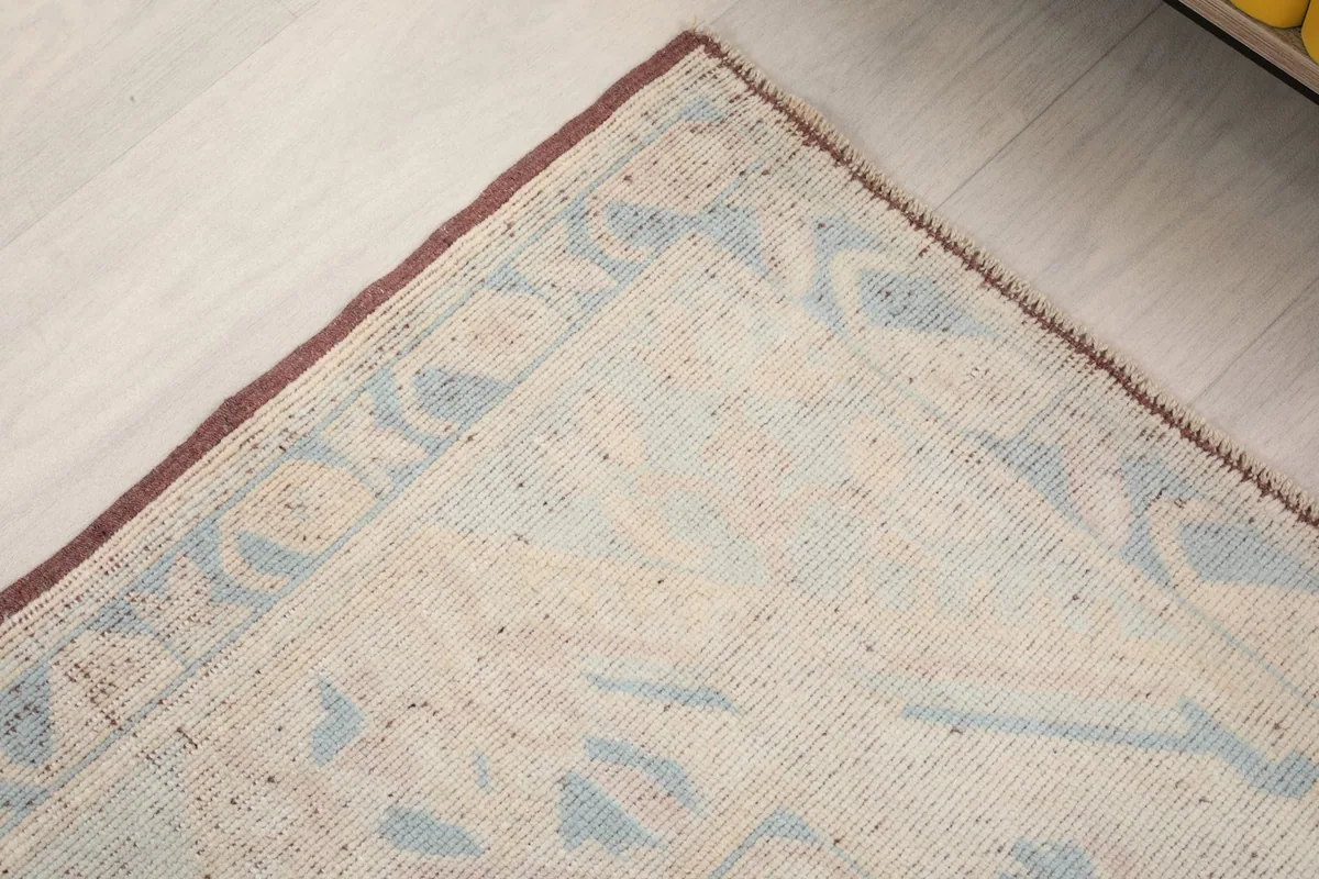 Close-up of the rug's border and a corner, revealing the rust color and geometric detail.