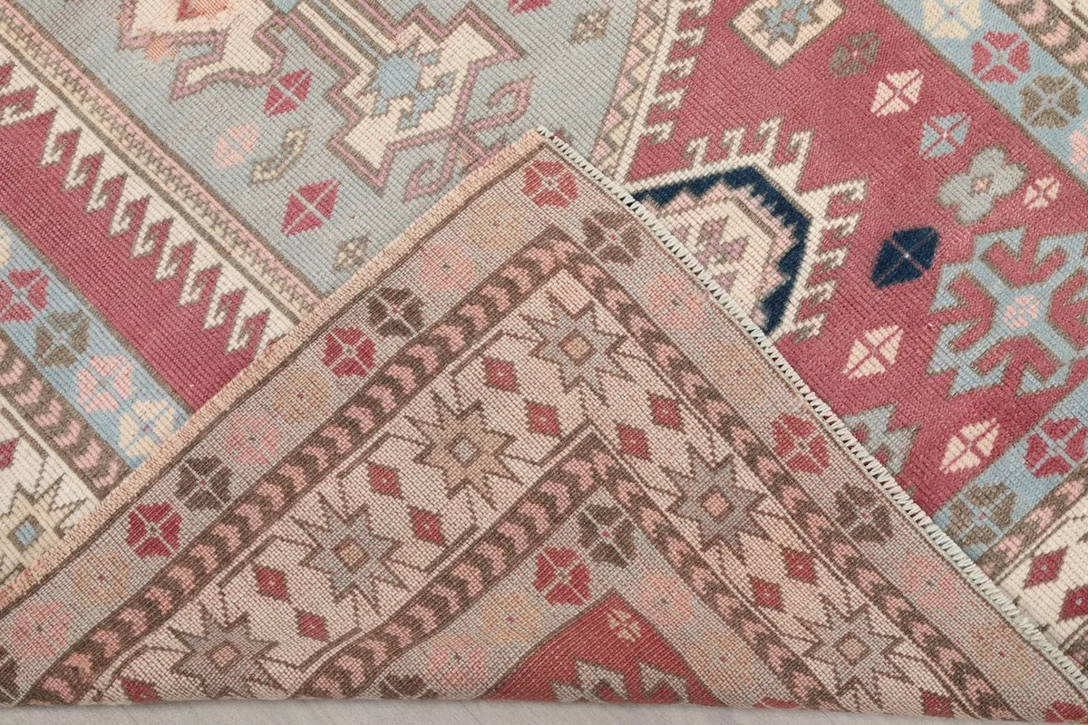 Corner of the rug folded back to reveal the back of the hand-knotted wool pile