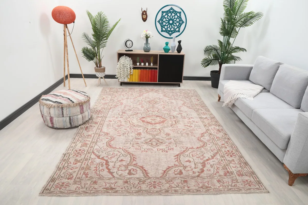 Vintage beige and rose rug in a modern living room setting with a light gray sofa and ottoman