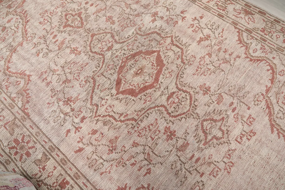 Overhead close-up of the central medallion and surrounding floral design in rose and rust colors