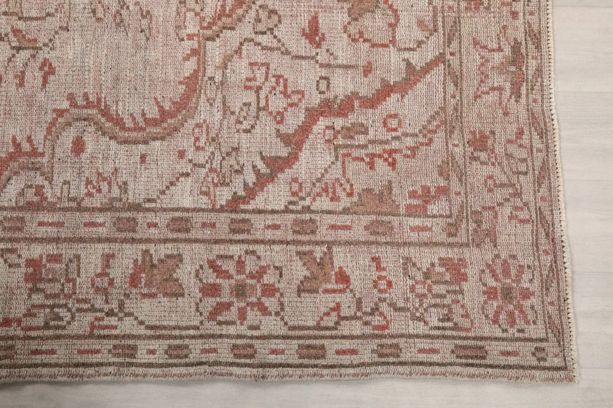 Detail of the rug's border with rose and brown floral motifs against the beige field