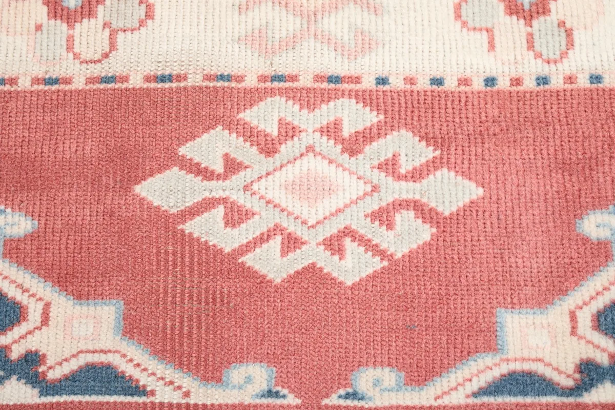 Close-up of a central geometric medallion on the red field with ivory and pink details