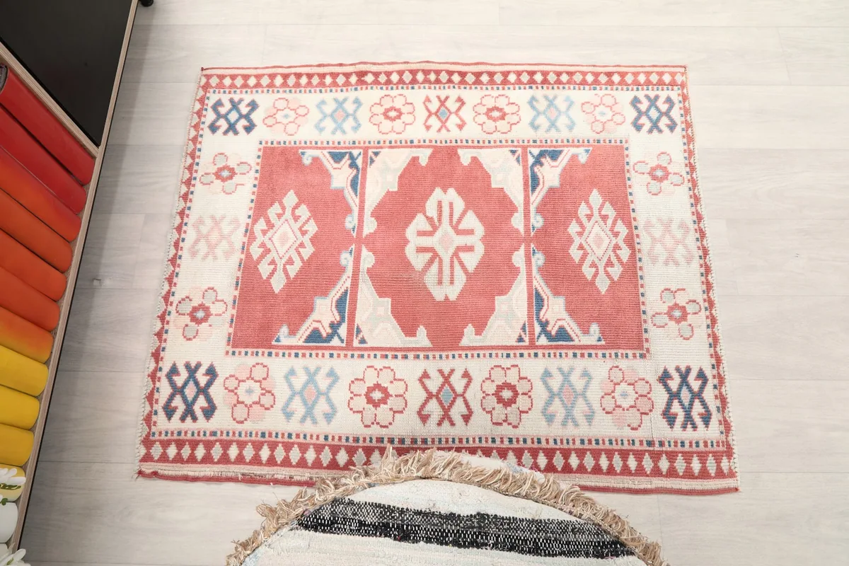 Full overhead view of the rug on a light floor, next to a striped pouf