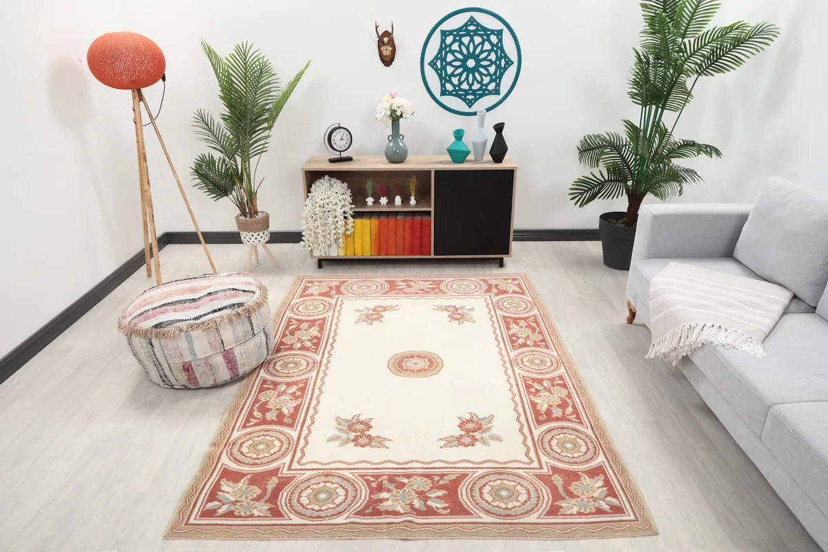 Vintage ivory and rust rug placed in a living room with a gray sofa and wooden cabinet