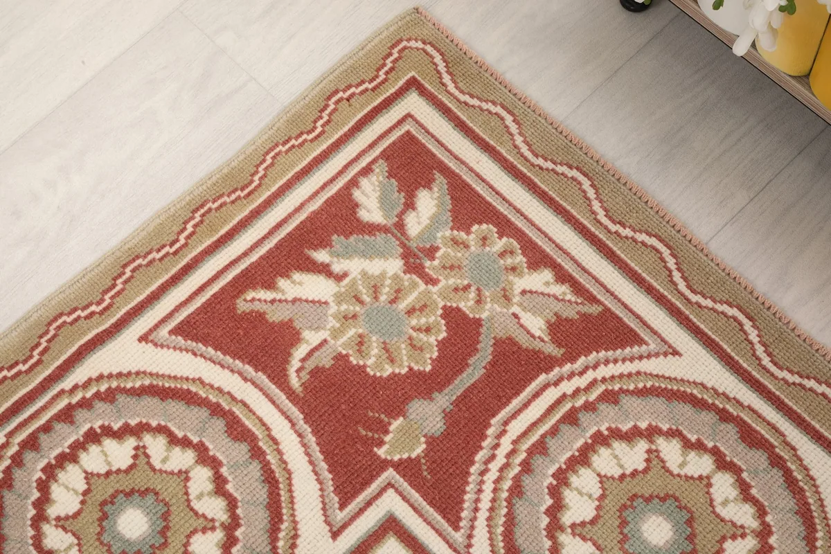 Corner detail of the rug's border, highlighting the floral design and wavy lines