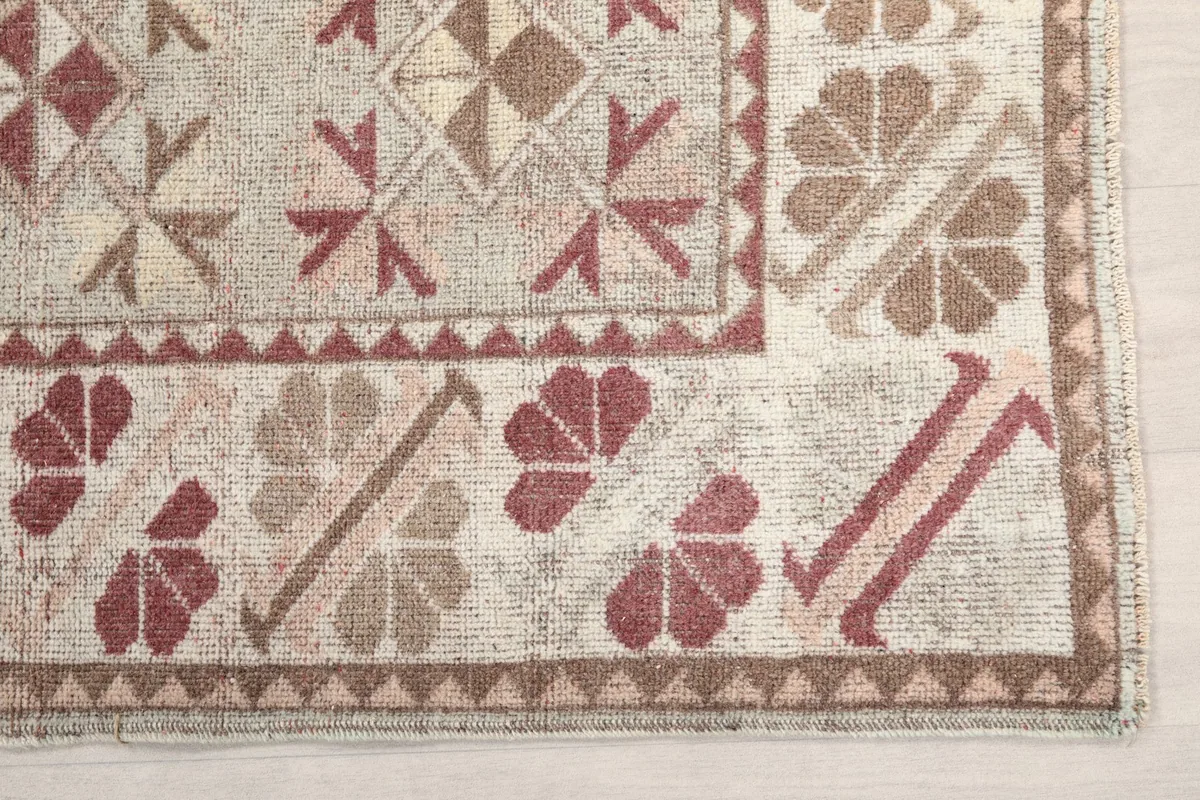 Detailed view of the rug's corner showing cream, rust, and brown geometric motifs