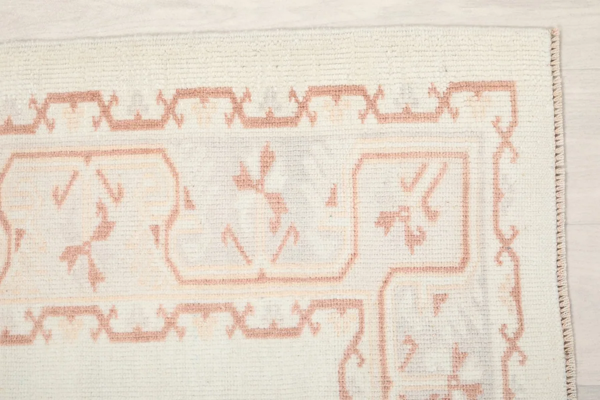 Detailed view of the rose geometric motifs in the rug's border