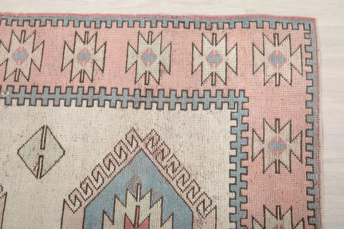 Close-up of the rug's corner, highlighting the pink border and geometric patterns