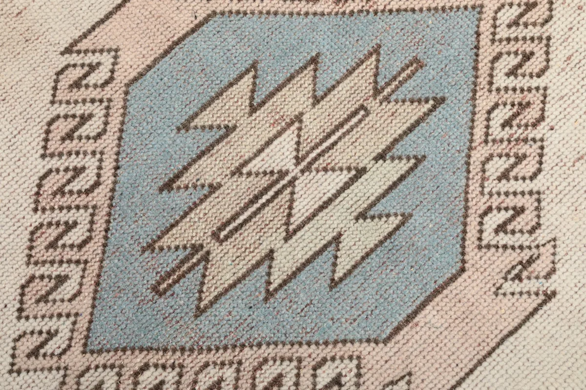 Extreme close-up of a blue and pink tribal geometric motif, showing wool pile