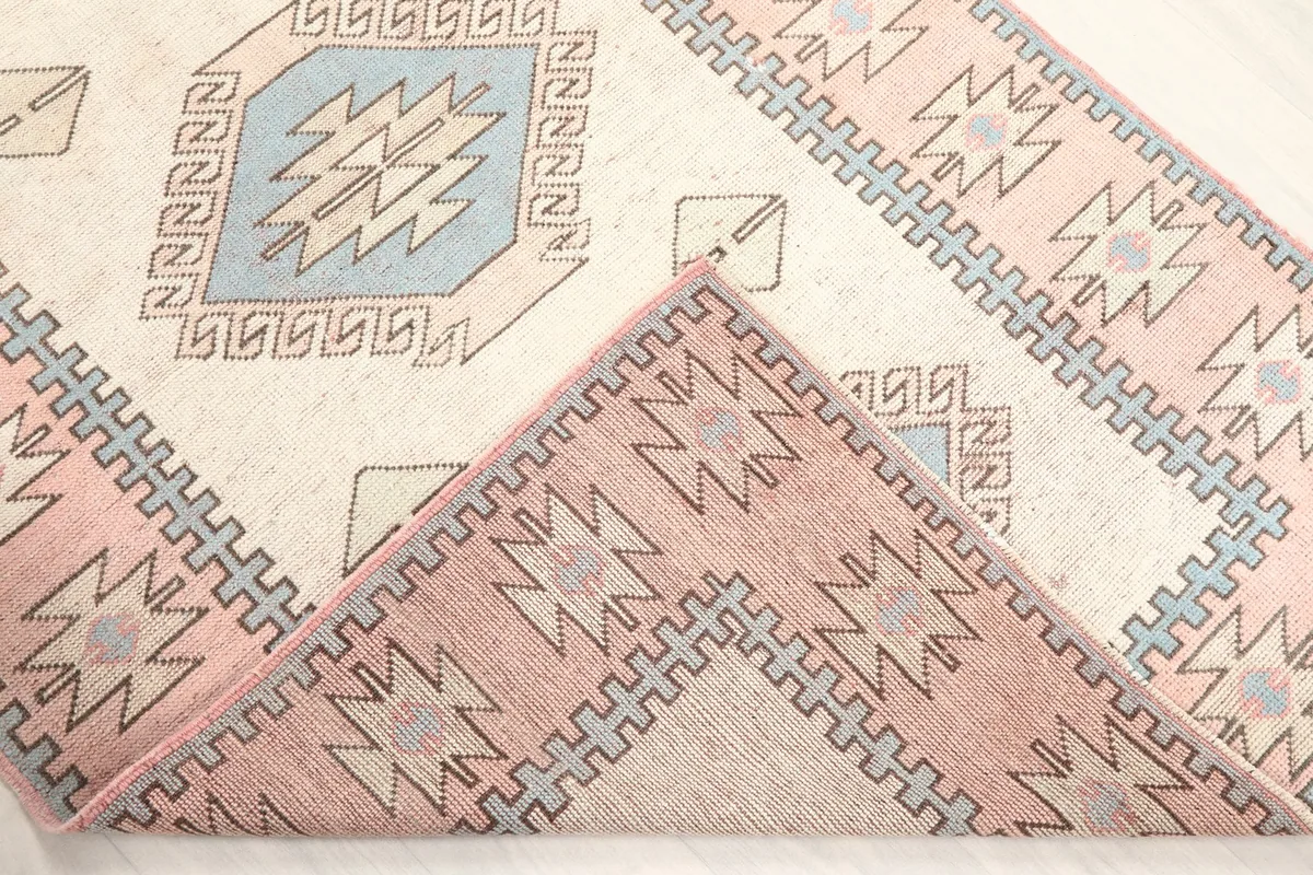 Corner of the rug folded back, revealing the hand-knotted wool pile and cotton foundation