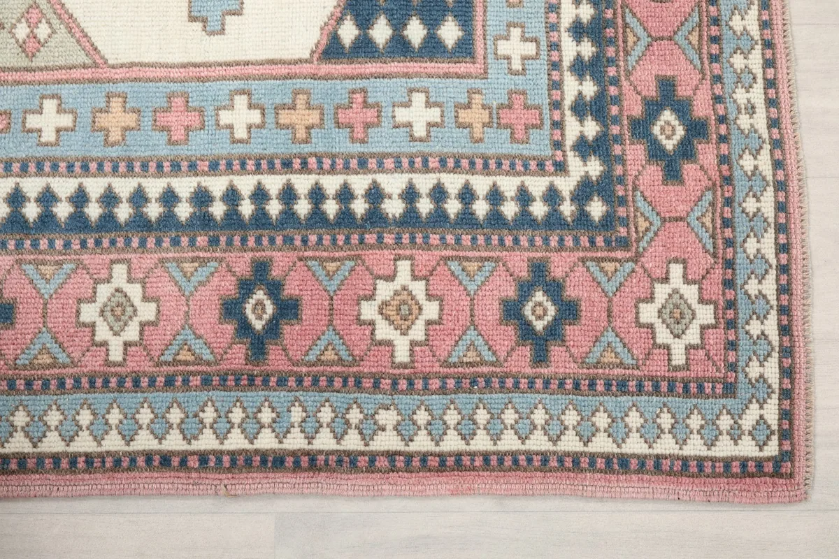 Close-up of the rug's intricate pink and navy blue border designs and corner details
