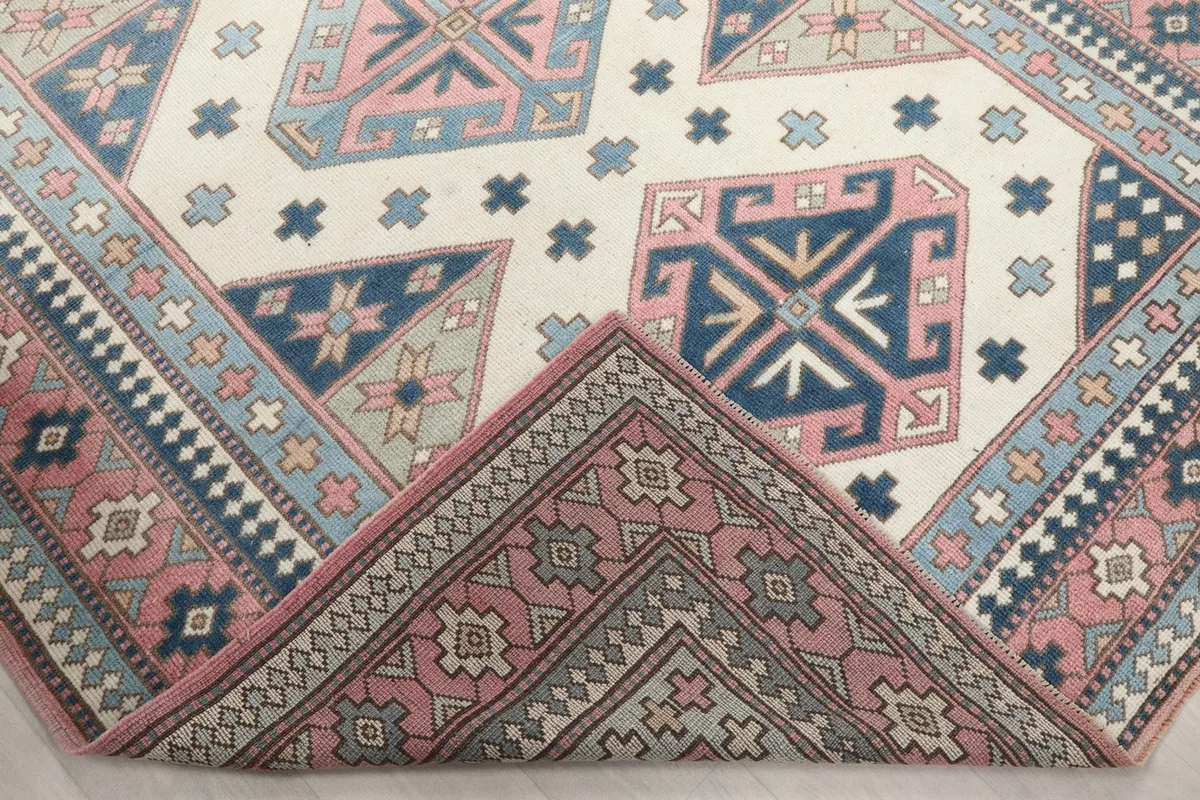 Corner of the rug folded back, revealing the wool pile texture and the cotton foundation