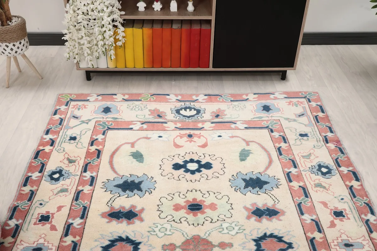 Frontal view of the ivory, rose, and blue vintage Anatolian rug in a room setting, showing its full design.