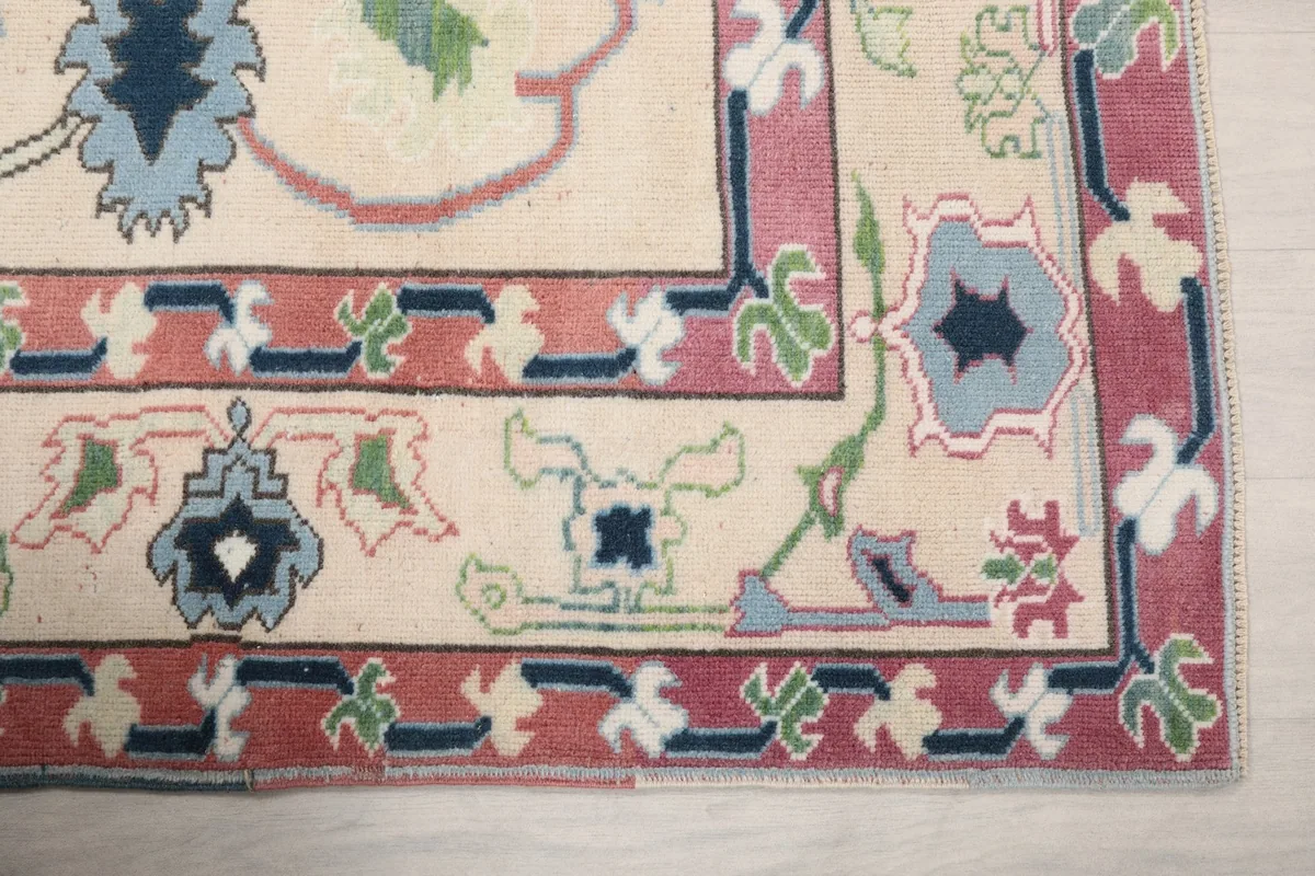 Detailed view of a corner of the rug, highlighting the rose border and blue and green motifs.