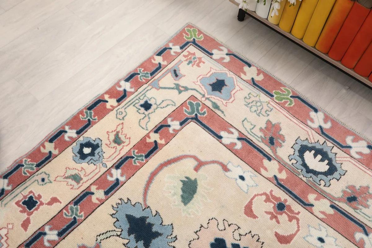 Corner detail of the rug's rose and blue border patterns and its ivory field.