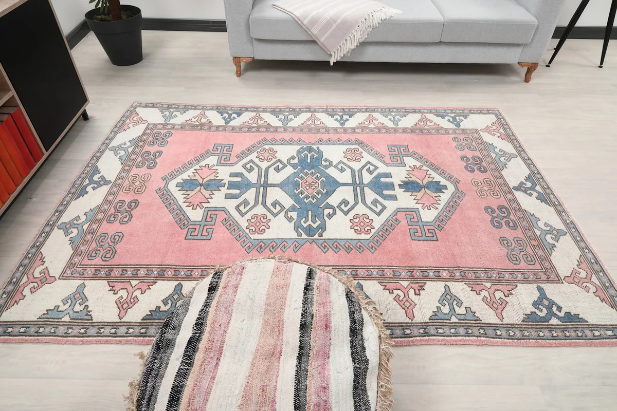 Full room view of the rose and blue rug centered, with decorative elements around it