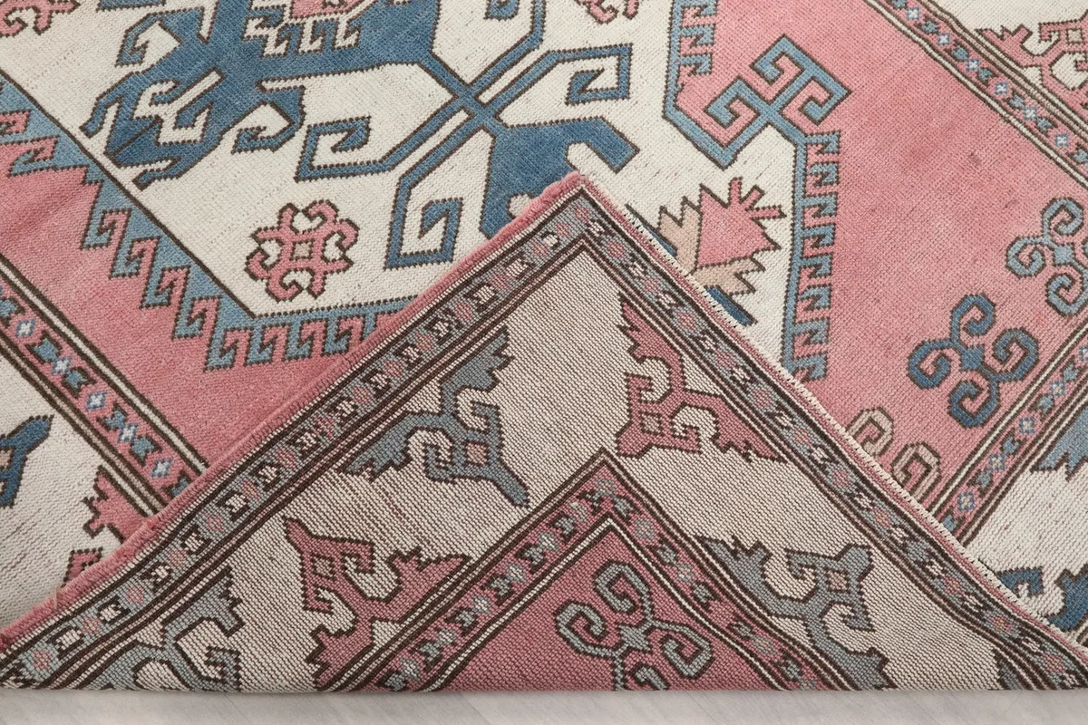 View of the rug folded back to show the cotton foundation and the reverse side of the knotting