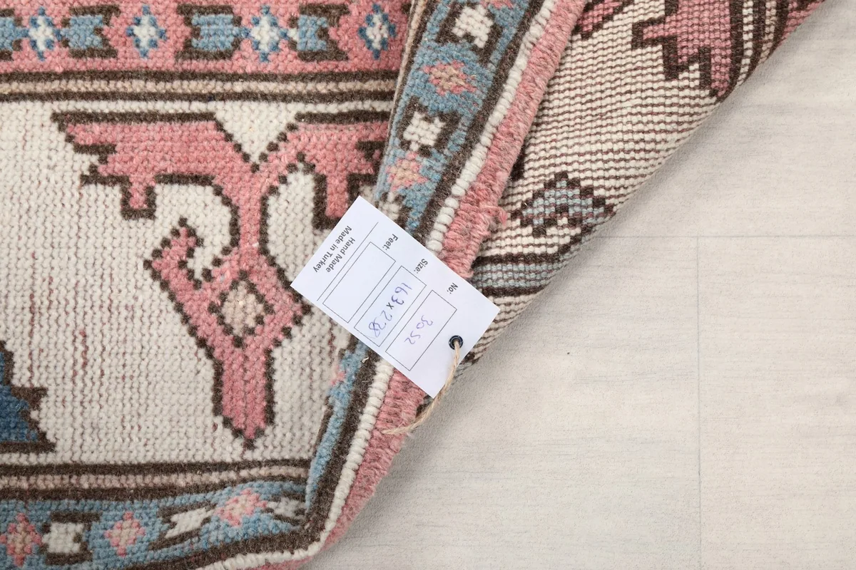 Detail of the rug's label with size information 163x238 cm attached to the back