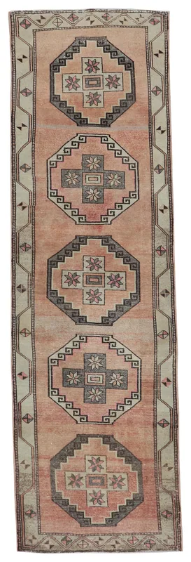 Full top view of a vintage rose and gray geometric Anatolian runner rug on a white background.