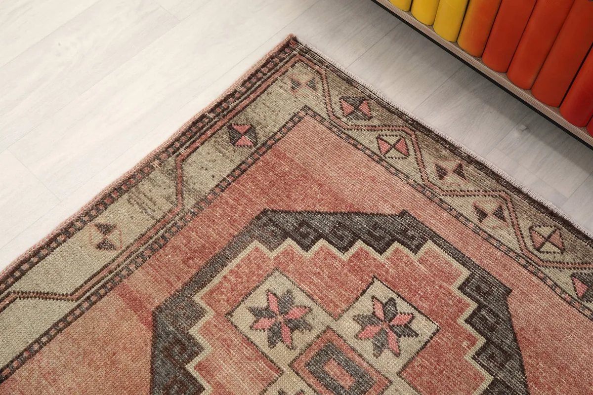 Corner view of the runner rug, showing the beige border and part of the rose field with patterns.
