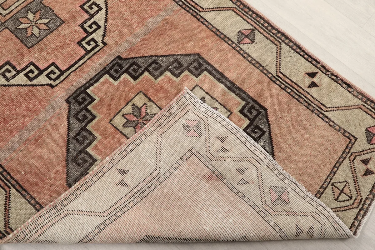 Folded corner of the rug revealing the hand-knotted cotton foundation and wool pile structure.